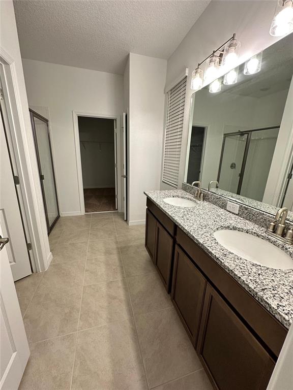 7004 Broad Wing Loop Howey-in-the-Hills, FL 34737 - Photo 8 of 10 a bathroom with a granite countertop sink a large mirror and a shower