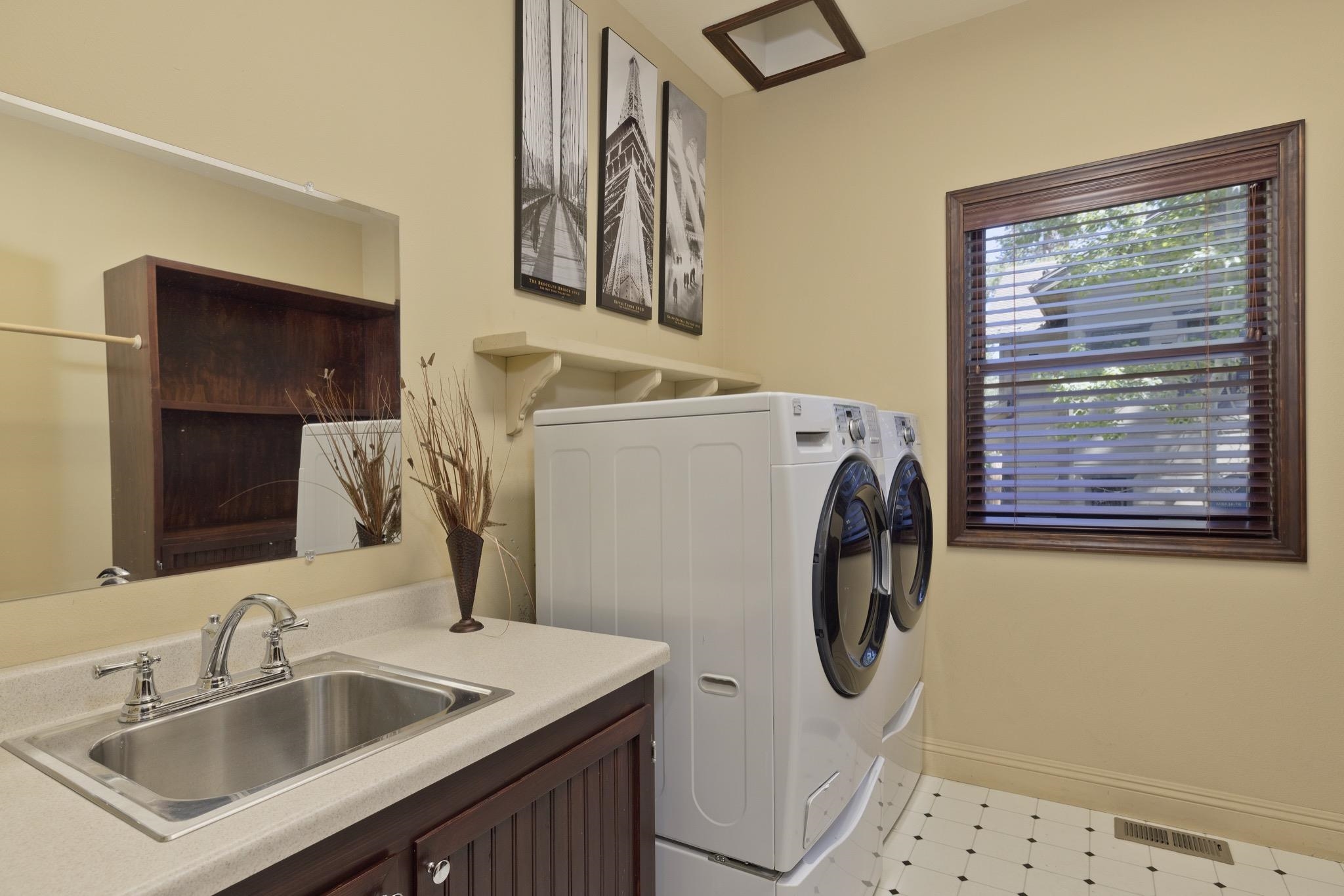 378 Ridge Way Mammoth Lakes, CA 93546 - Photo 35 of 43 Dedicated laundry space featuring a utility sink, dark wood-finish cabinetry, a window with wood-finish blinds, and patterned tile flooring
