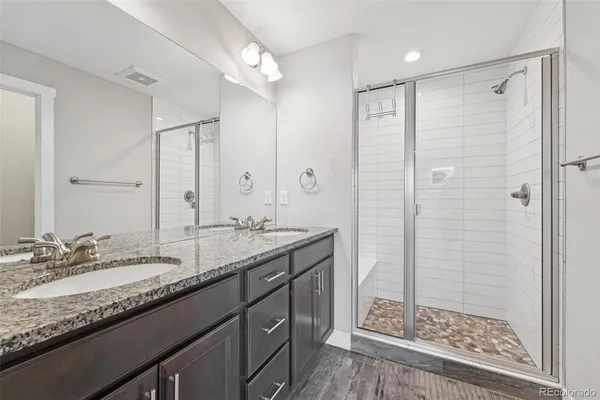 a bathroom with a granite countertop sink mirror and shower