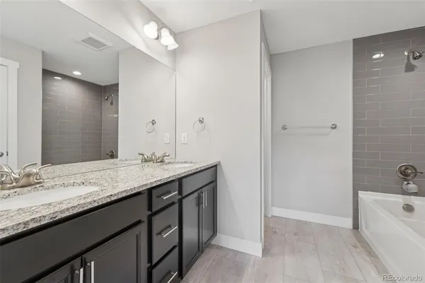 a bathroom with a granite countertop sink mirror and bathtub