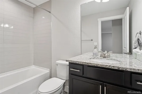 a bathroom with a granite countertop sink toilet a large mirror a bathtub and shower