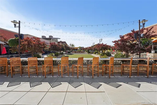 a roof deck view with lawn chairs plants and large trees