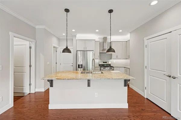 a large white kitchen with kitchen island a stove a sink a refrigerator and chairs