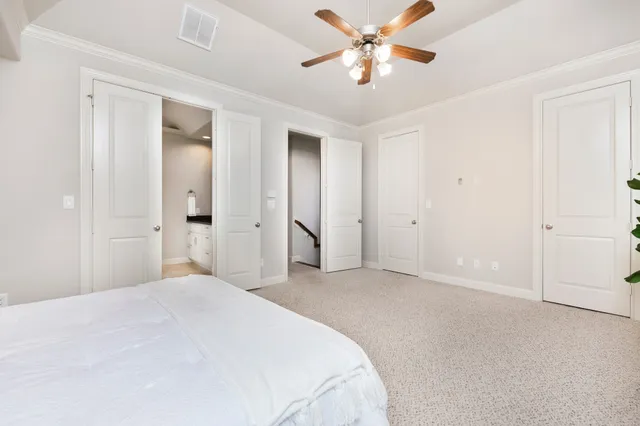 a bedroom with a large bed and a chandelier fan