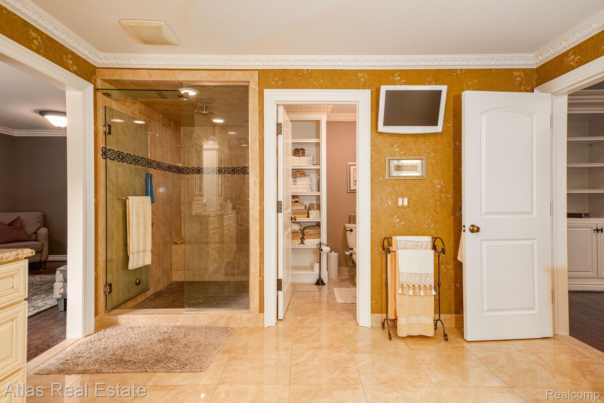 10380 South State Road Goodrich, MI 48438 - Photo 65 of 87 Spacious bathroom featuring a glass-enclosed shower with stone tile, a built-in shower bench, and a decorative border