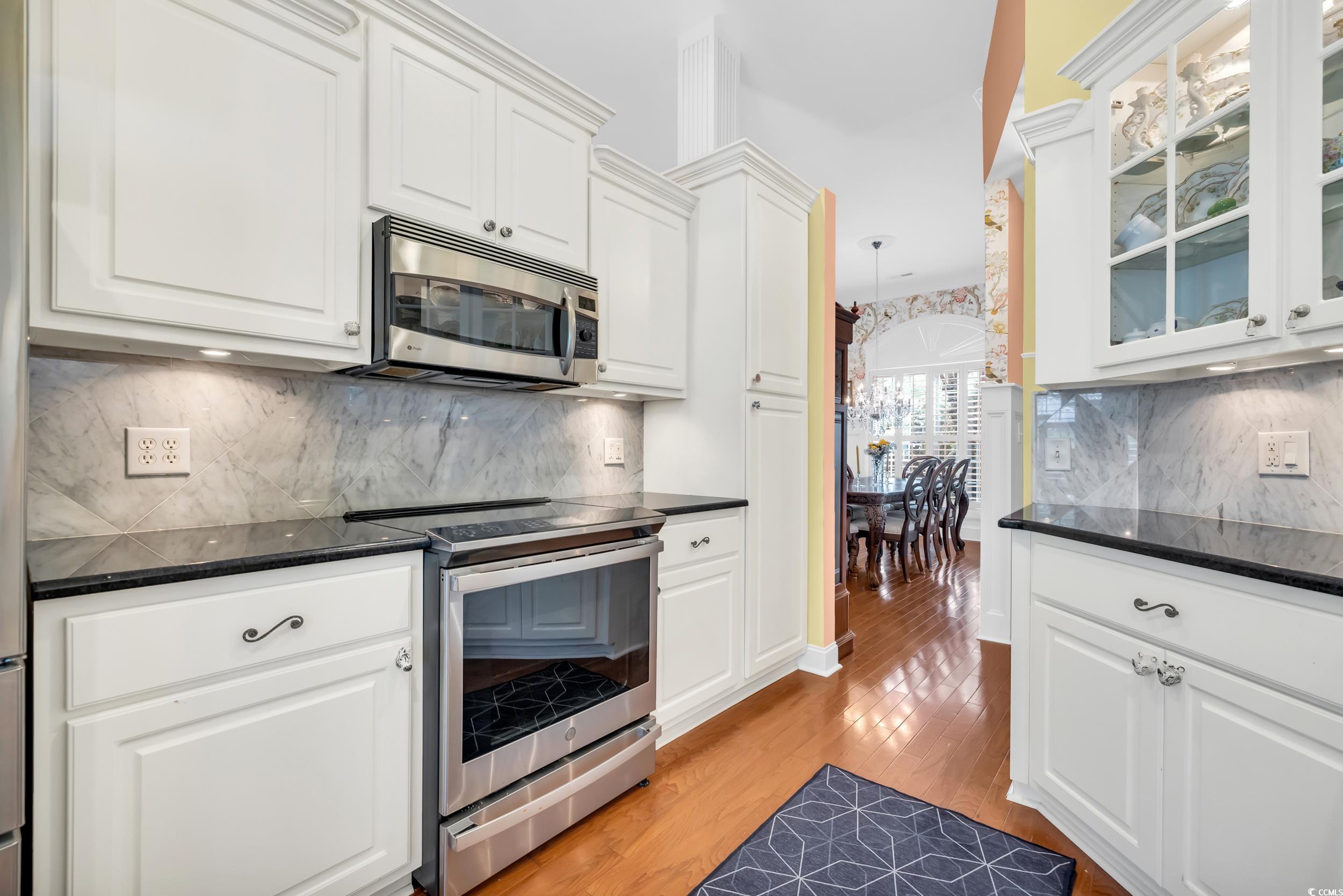 3112 Bayhaven Drive Myrtle Beach, SC 29579 - Photo 15 of 40 Kitchen featuring appliances with stainless steel finishes, backsplash, white cabinetry, light wood finished floors, and dark stone counters