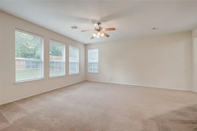 an empty room with chandelier fan and windows