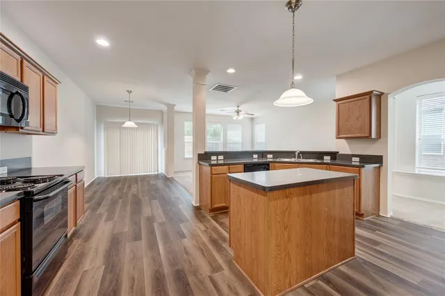 a large kitchen with stainless steel appliances granite countertop a stove a sink dishwasher and a microwave oven with wooden floor