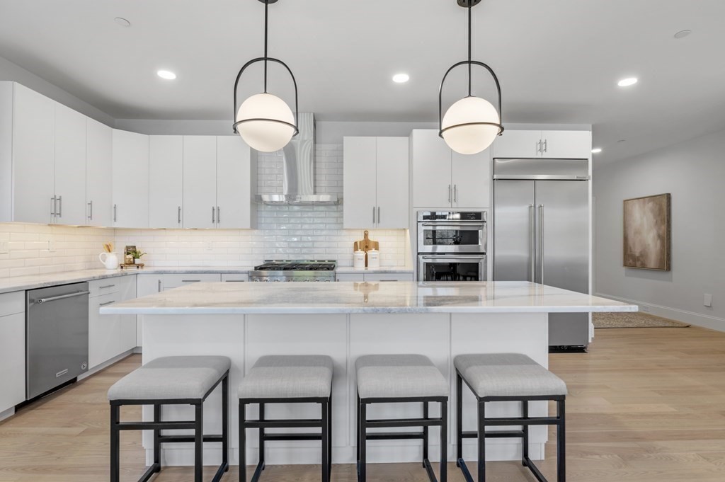 32 Pne Hl Road, Unit 32 Wenham, MA 01984 - Photo 15 of 36 a kitchen with a dining table chairs cabinets and stainless steel appliances