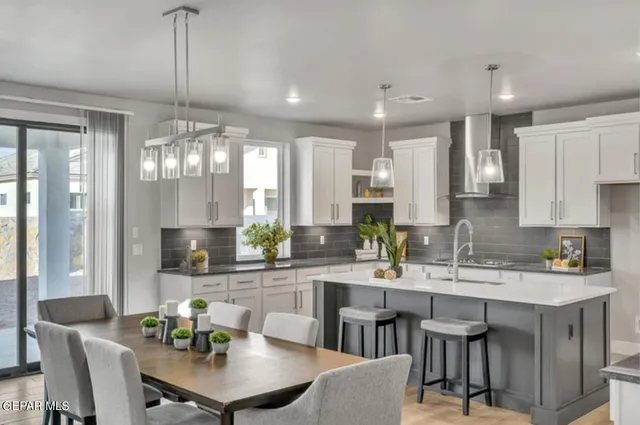 a kitchen with stainless steel appliances kitchen island granite countertop a dining table chairs and white cabinets