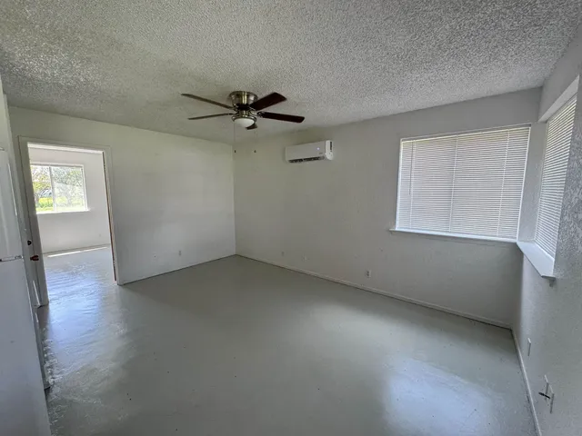 en empty room with windows and ceiling fan