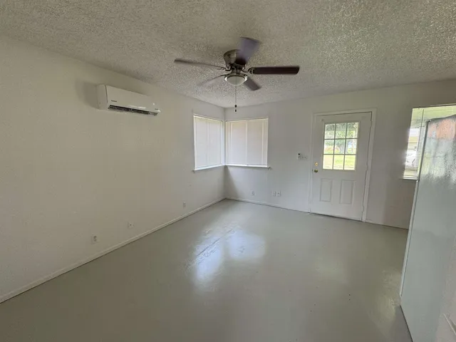 an empty room with windows and ceiling fan