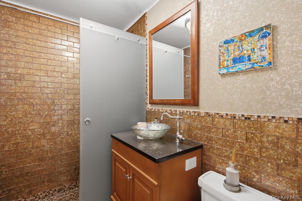 30 Stoner Avenue, Unit 1S Great Neck, NY 11021 - Photo 18 of 29 a bathroom with a granite countertop sink a toilet and a mirror