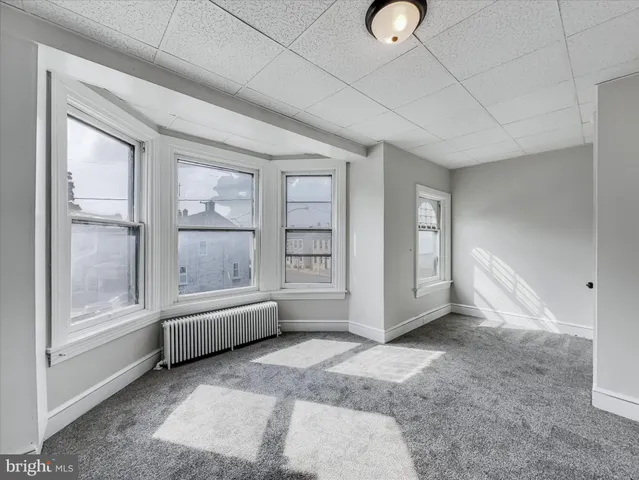 a view of an empty room with window and cabinet