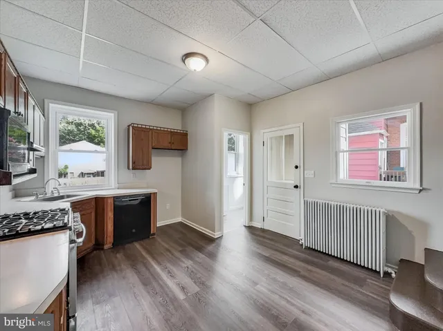 a kitchen with stainless steel appliances granite countertop a stove a sink dishwasher and a refrigerator with wooden floor