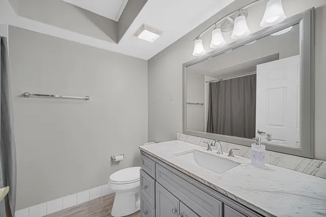 a bathroom with a granite countertop sink a toilet and a mirror