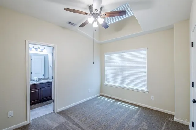 an empty room with windows and fan