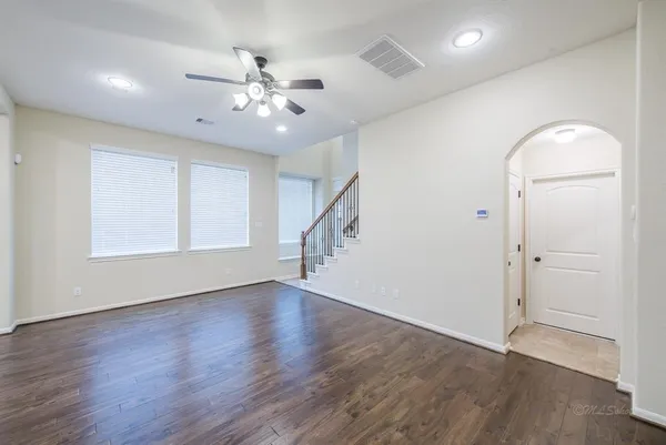 an empty room with wooden floor fan and windows