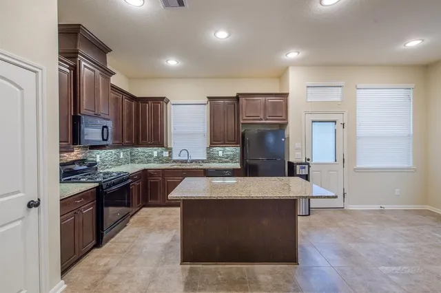 a large kitchen with stainless steel appliances kitchen island granite countertop wooden cabinets a granite counter tops and a large window