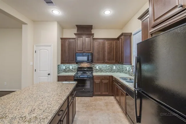 a kitchen with stainless steel appliances granite countertop a refrigerator and a sink