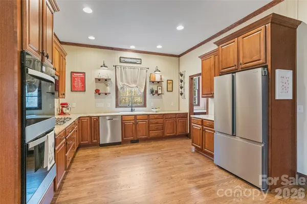 a kitchen with stainless steel appliances granite countertop a refrigerator a stove and a sink with large window
