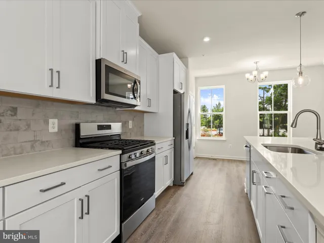 a kitchen with stainless steel appliances granite countertop white cabinets a sink dishwasher a stove and a refrigerator with wooden floor