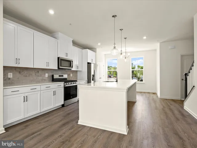 a large kitchen with white cabinets stainless steel appliances a sink and a stove