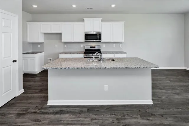 a kitchen with kitchen island granite countertop a stove top oven a sink and dishwasher