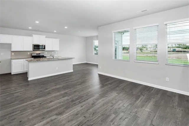 a kitchen with stainless steel appliances a stove top oven a sink a refrigerator and a window