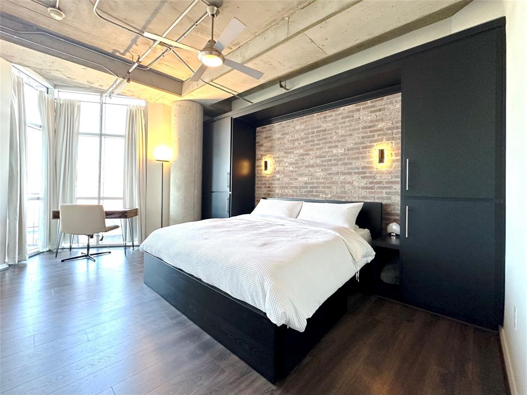 1001 Belleview Street, Unit 307 Dallas, TX 75215 - Photo 4 of 36 Large primary bedroom has seating area with blackout curtains, brick feature wall with reading lights.