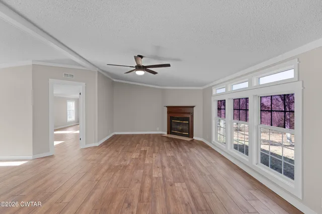 a view of an empty room with a window and wooden floor
