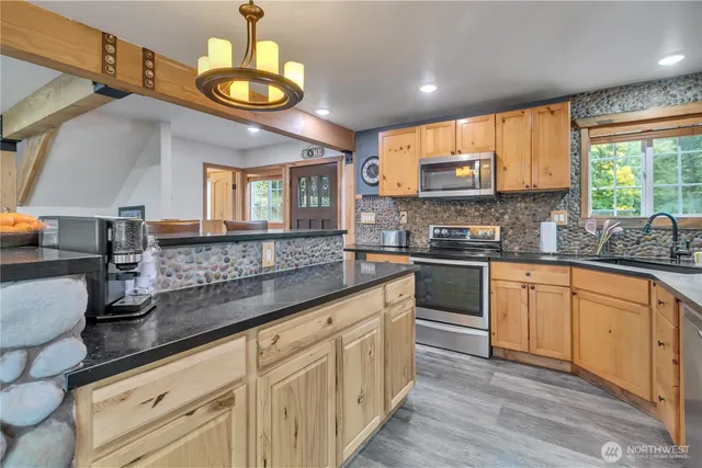 a kitchen with stainless steel appliances granite countertop a stove a sink dishwasher and white cabinets with wooden floor