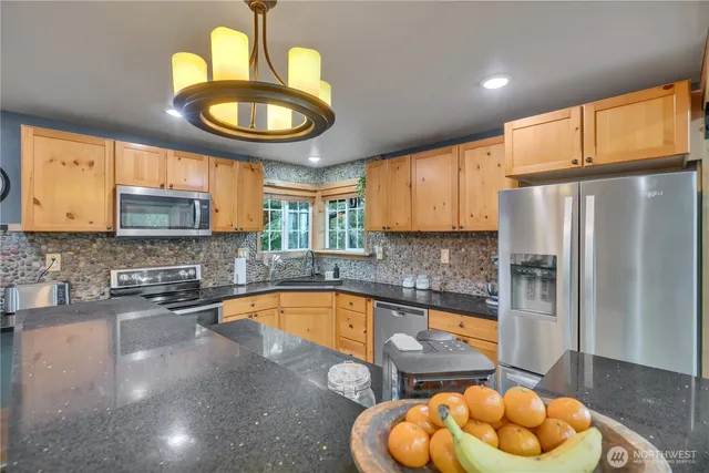 a kitchen with stainless steel appliances granite countertop a sink a refrigerator and a wooden cabinets