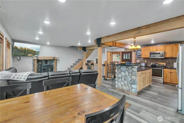 a kitchen with stainless steel appliances kitchen island granite countertop a table chairs sink and cabinets