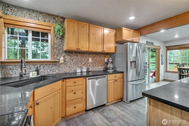 a kitchen with stainless steel appliances granite countertop a refrigerator a sink dishwasher a stove and white countertops with wooden floor