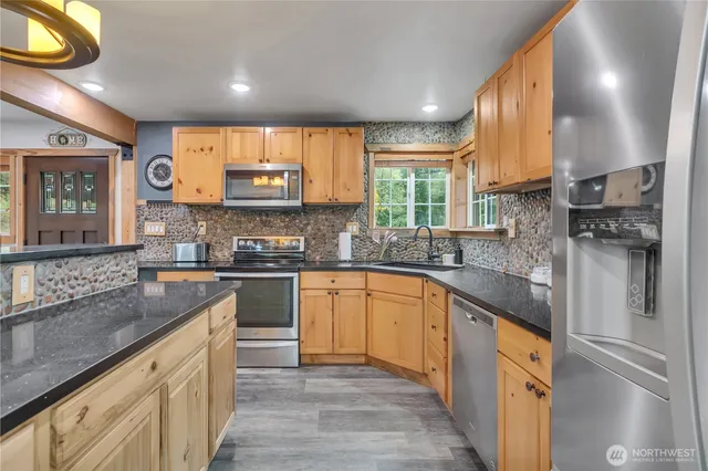 a kitchen with stainless steel appliances granite countertop a sink a stove and cabinets