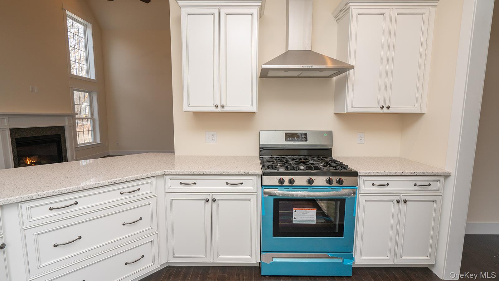 43 Malloy Road Wallkill, NY 12589 - Photo 7 of 50 Kitchen featuring stainless steel gas stove, wall chimney exhaust hood, white cabinetry, a glass covered fireplace, and light stone countertops