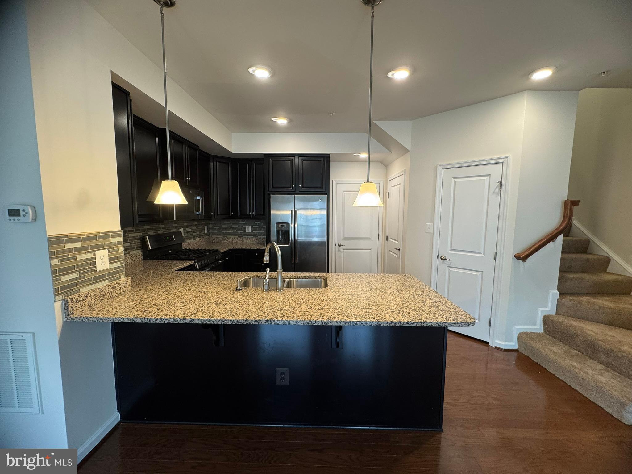 6436 Walcott Lane Frederick, MD 21703 - Photo 7 of 27 a kitchen with kitchen island granite countertop wooden cabinets a sink and a refrigerator