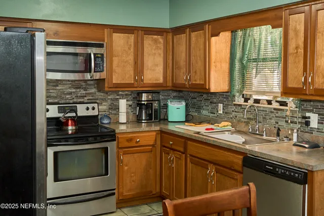 a kitchen with stainless steel appliances granite countertop a stove top oven a sink dishwasher a refrigerator and cabinets with wooden floor