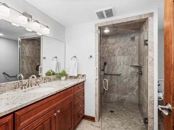 a bathroom with a granite countertop sink a mirror and a shower