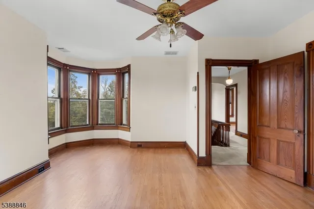 a view of an empty room with a window and wooden floor
