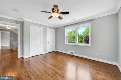 a view of empty room with wooden floor and fan