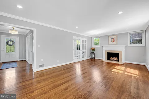 a view of an empty room with wooden floor fireplace and a window