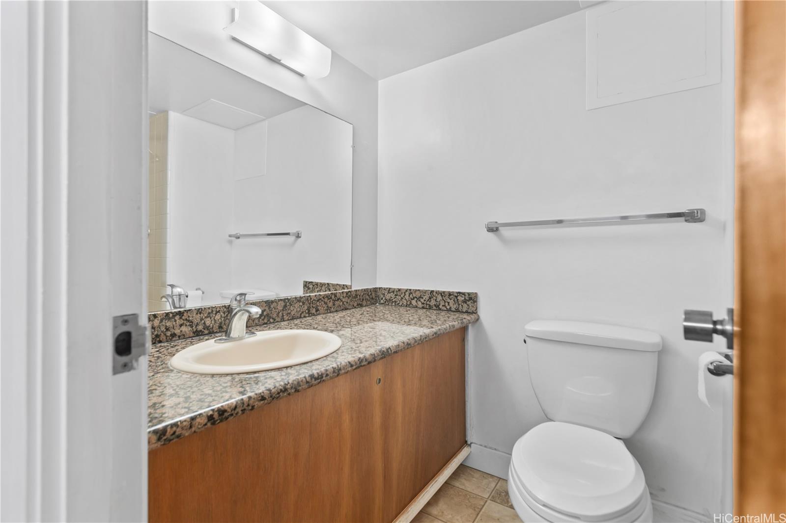 1018 Lunalilo Street, Unit 603 Honolulu, HI 96822 - Photo 5 of 12 a bathroom with a granite countertop toilet sink and mirror