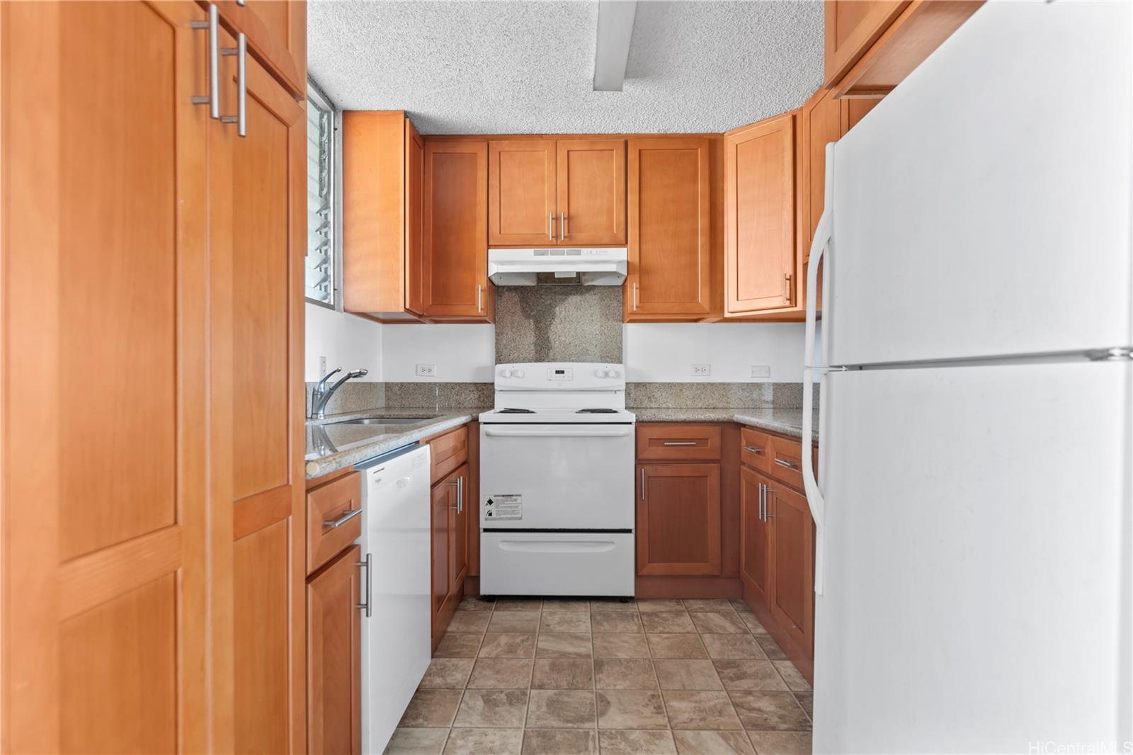 1018 Lunalilo Street, Unit 603 Honolulu, HI 96822 - Photo 6 of 12 a kitchen with a stove a sink and a refrigerator