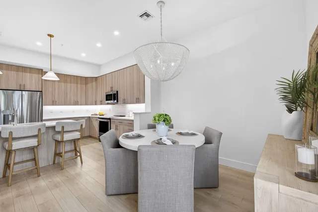 a kitchen with stainless steel appliances kitchen island granite countertop a dining table chairs and a refrigerator