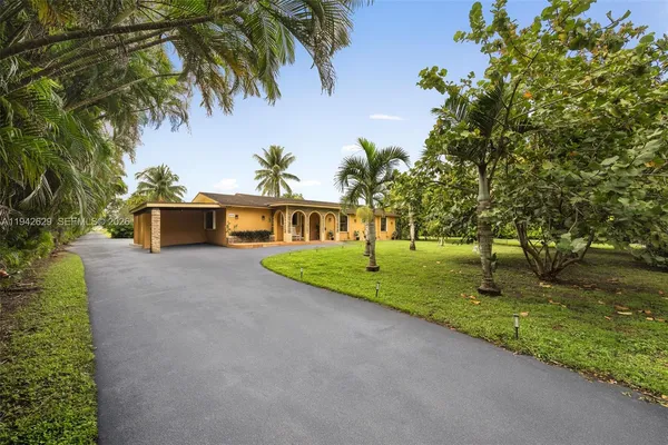 a view of a house with a yard and palm trees