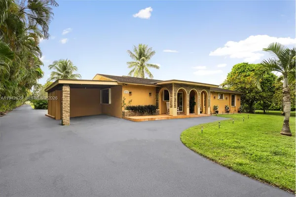 a front view of a house with a garden and trees
