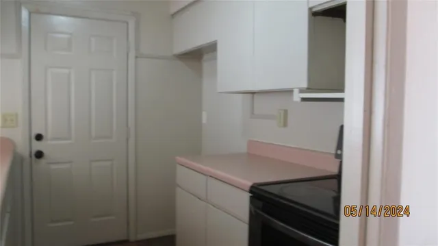 a kitchen with white cabinets and black appliances