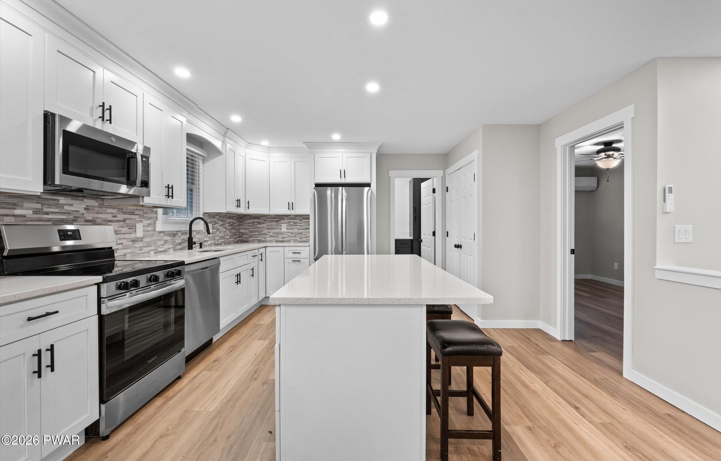 9 High Point Court Lake Ariel, PA 18436 - Photo 12 of 40 a kitchen with stainless steel appliances kitchen island granite countertop a stove top oven a sink dishwasher a refrigerator and a dining table with wooden floor